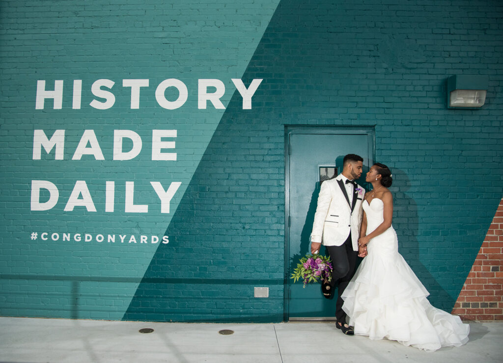 congdon yards courtyard bride and groom kissing in front of history made daily mural