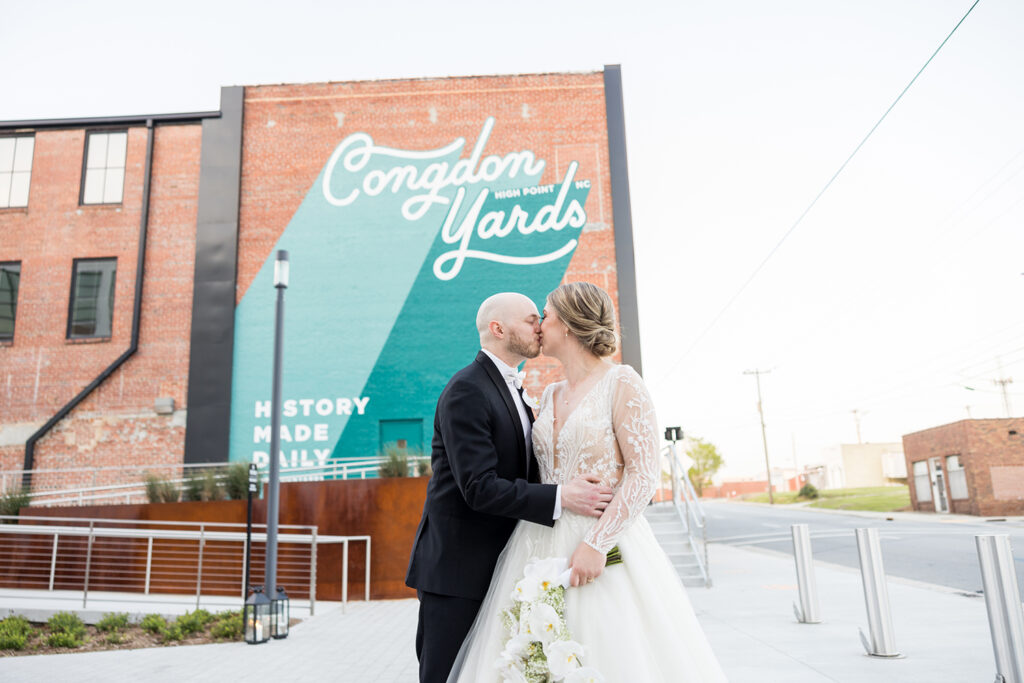 congdon yards courtyard bride and groom kissing in front of mural