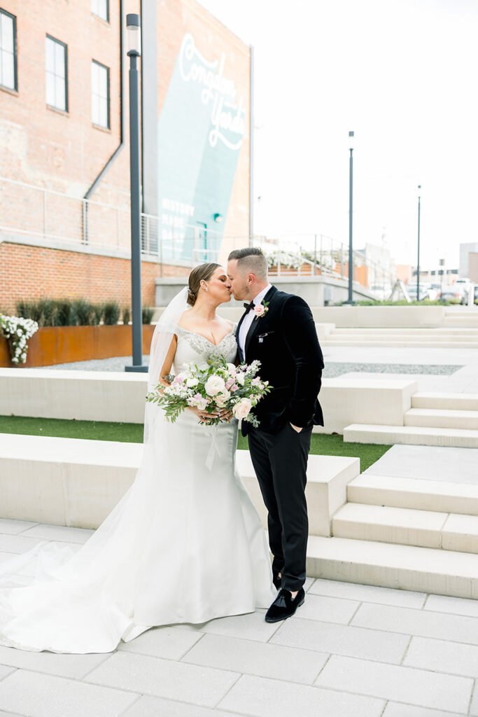 congdon yards courtyard bride and groom kissing with bouquet