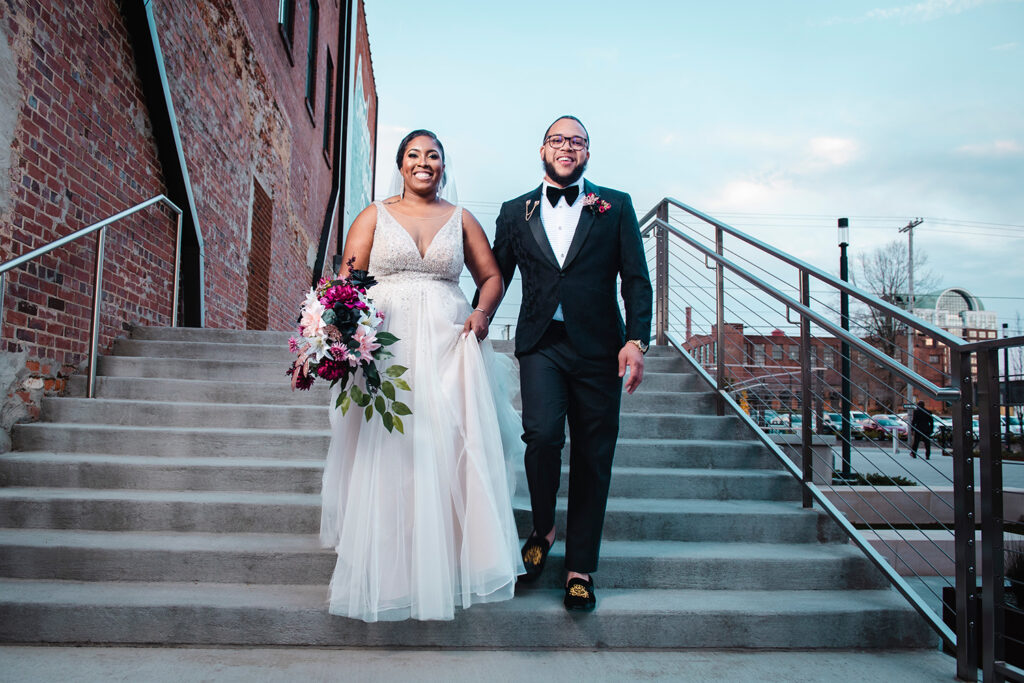 congdon yards courtyard bride and groom walking down stairs smiling