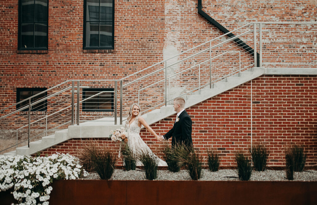 congdon yards courtyard bride and groom walking in front of brick