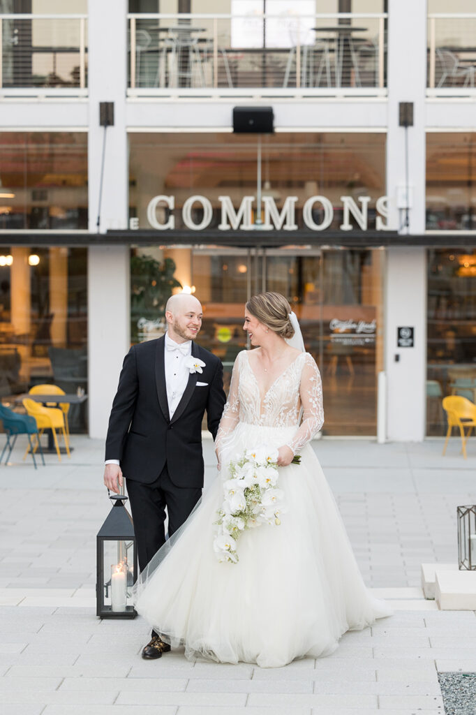 congdon yards courtyard bride and groom walking with the commons sign in background