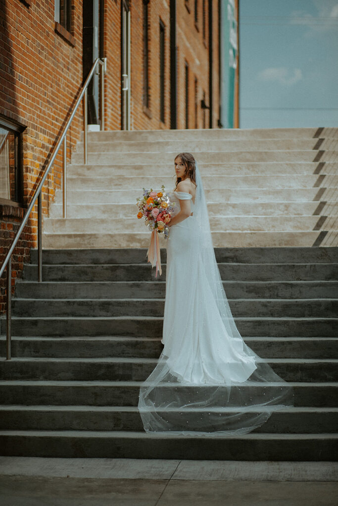 congdon yards courtyard bride posing on stairs with bouquet