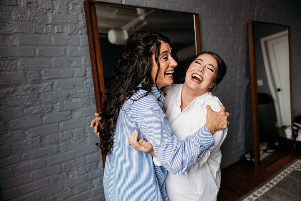 congdon yards luxe suite bride laughing with bridesmaid and hugging