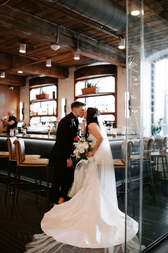 congdon yards the factory bride and groom sitting at bar kissing