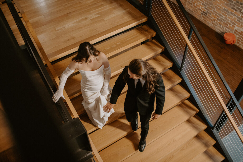 congdon yards the factory bride and groom walk down stairs holding hands